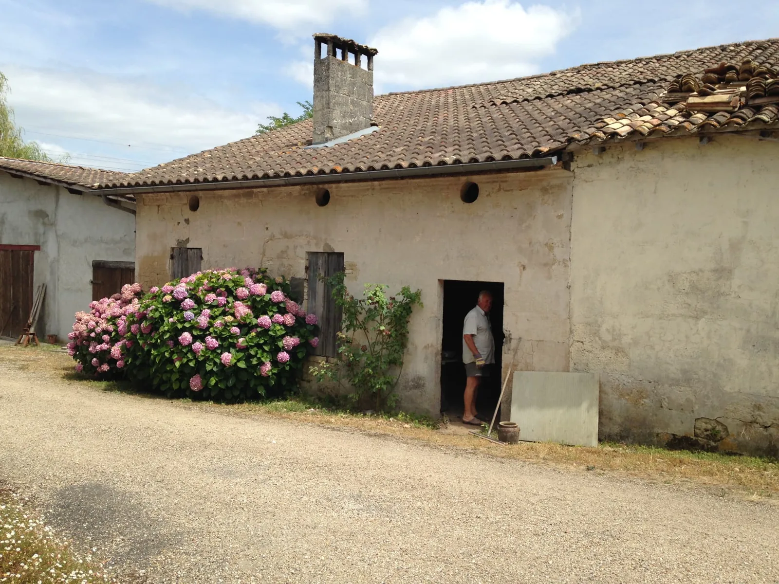 État existant du bâtiment à Abzac avant l'aménagement intérieur du duplex : façade enduite, volets bois et cour en gravier